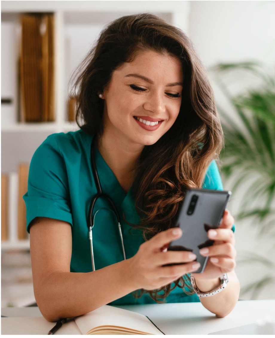 Nurse Smiling at Smart Phone at Desk